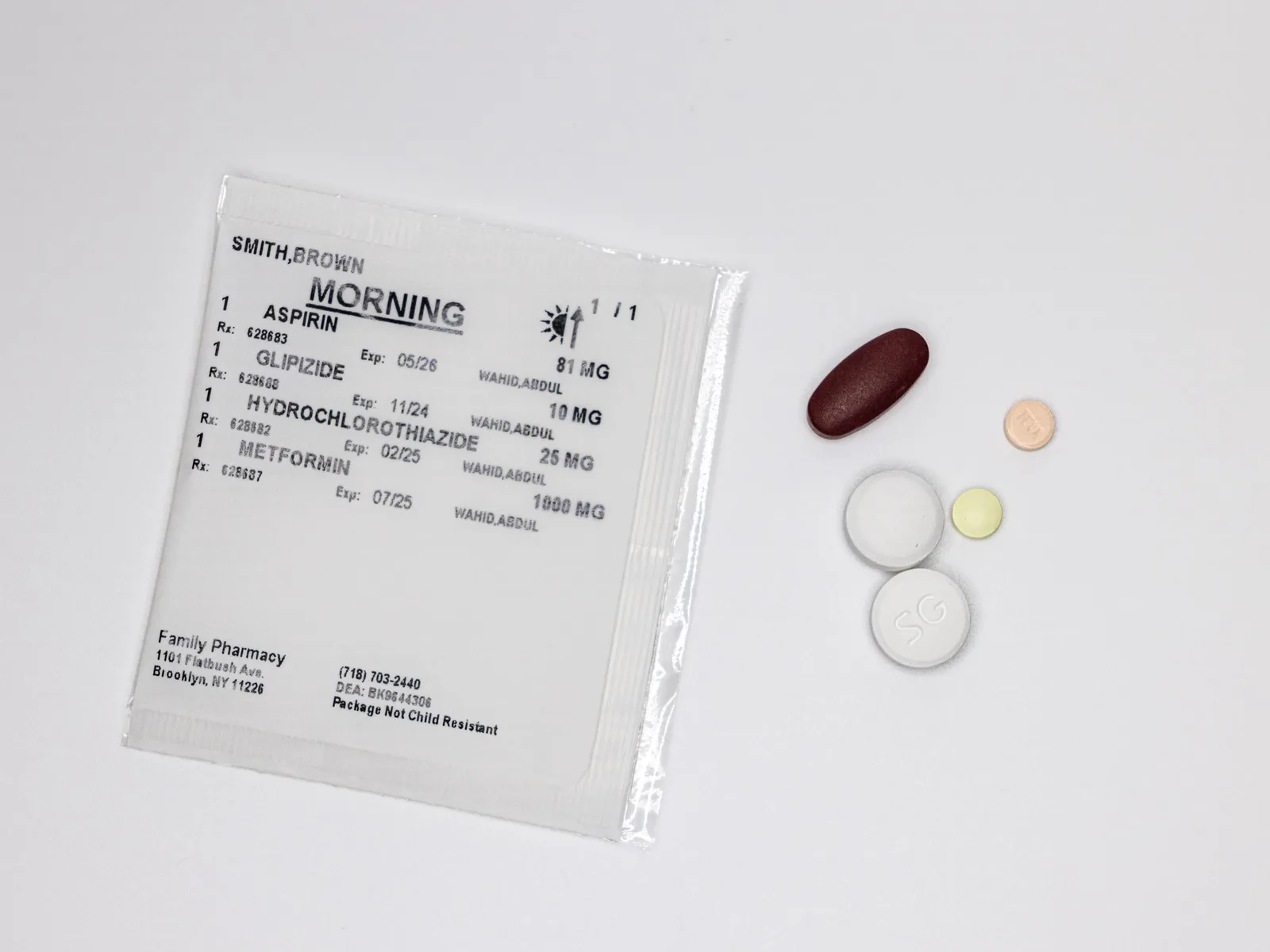 Sealed Family Pharmacy multi-dose pouch labeled Morning with the patient's medications listed, next to the sorted pills