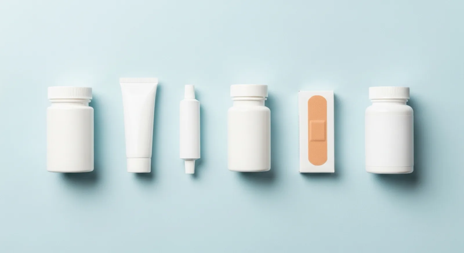 Assorted over-the-counter bottles, ointment tube, and bandages on a light blue background
